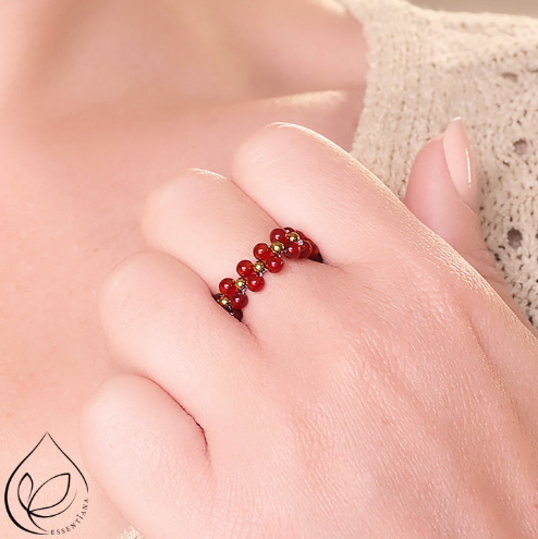 Bague en cornaline rouge avec petites perles dorées portée sur une main, bague taille 56 mm, perles doublées de 3 mm, fond clair et lumineux, bijou artisanal, élégant et énergétique