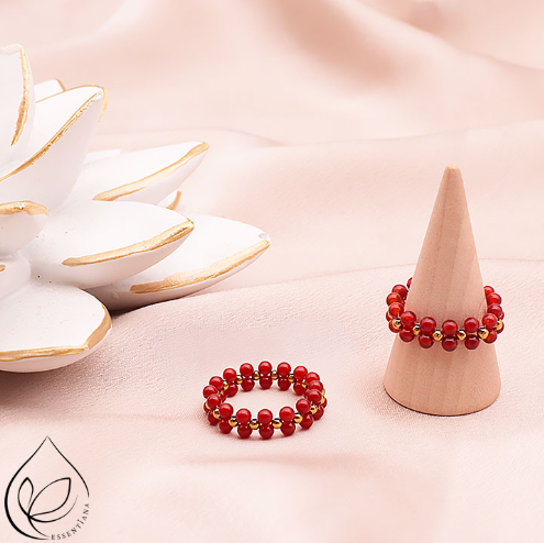 Deux bagues en cornaline rouge avec perles dorées sur un fond clair : une posée à plat et l’autre sur un petit présentoir en forme de cône, perles naturelles doublées de 3 mm, bagues artisanales, bijou éclatant et raffiné.