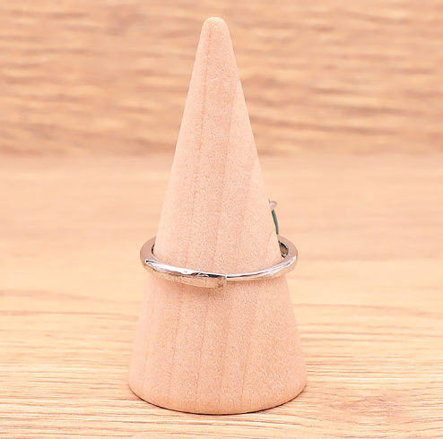 Bague en malachite naturelle du Congo présentée sur un petit cône, vue de dos, montrant la monture réglable en laiton argenté, pierre ovale verte de 14 x 0,7 mm, fond clair et lumineux, bijou artisanal raffiné.