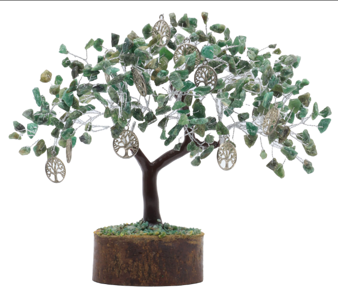 Une sculpture artisanale représentant un arbre de vie de 22 cm de largeur sur 25 cm de hauteur. Le feuillage : La cime de l'arbre est dense, composée de multiples petites pierres brutes de jade d'un vert clair et tendre. Ces minéraux aux formes irrégulières et naturelles sont solidement fixés sur des branches en fil métallique argenté très fin. Les ornements : Huit petits pendentifs métalliques argentés et circulaires, finement ciselés en forme d'arbre de vie miniature, sont suspendus aux branches et se mêlent aux pierres de jade. Le tronc : Le tronc central est lisse, d'un brun foncé brillant, imitant l'écorce d'un jeune arbuste. Il se sépare harmonieusement en deux branches maîtresses pour soutenir la ramure. Le socle : L'arbre repose sur une base cylindrique en bois sombre et épais, dont le sommet est recouvert d'un lit de minuscules graviers de jade vert et jaune. Arrière-plan : Le fond est entièrement blanc et épuré, mettant pleinement en valeur les nuances vertes du jade et l'éclat argenté des branches.